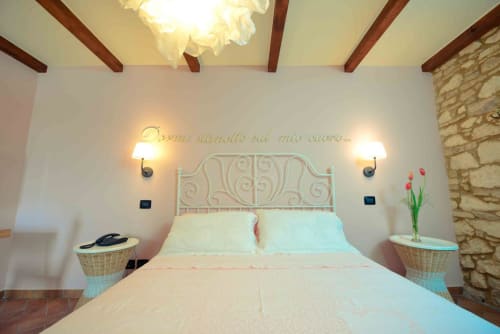 Cozy bedroom at Casale 905 in Crecchio with wrought iron bed, exposed beams, and warm lighting