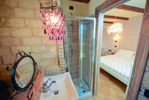 Modern bathroom at Casale 905 B&B in Crecchio with pink chandelier, shower, and view to bedroom