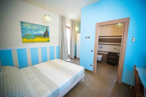 Modern bedroom at Casale 905 B&B in Crecchio with blue striped headboard, white bedding, and ensuite bathroom