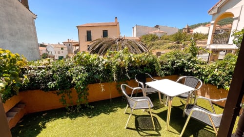 Terraza soleada con mesa, sillas y plantas exuberantes en Casa Rural Villa del Jerte, El Torno, Cáceres