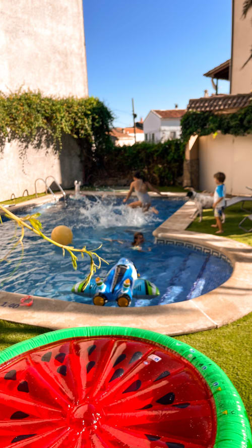 Niños jugando en la piscina del jardín de Casa Rural Villa del Jerte con juguetes inflables y tumbonas