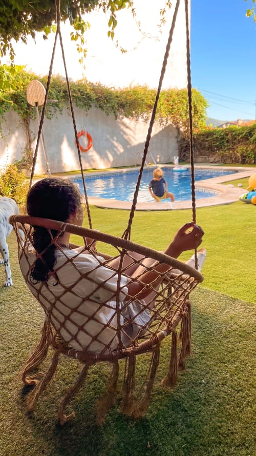Niño en columpio de macramé con vista a la piscina en Casa Rural Villa del Jerte, El Torno Cáceres