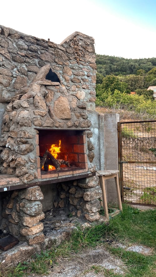 Chimenea rústica al aire libre con llamas activas en Casa Rural Villa del Jerte, El Torno Cáceres