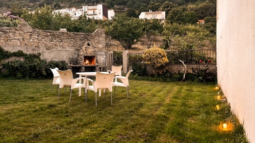 Zona de descanso al aire libre en Casa Rural Villa del Jerte con sillas blancas alrededor de una chimenea en El Torno, Cáceres