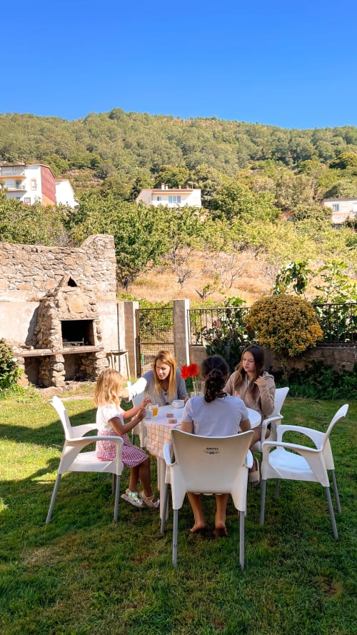 Tres mujeres cenando al aire libre en Casa Rural Villa del Jerte, Cáceres, España, con chimenea de piedra y vistas a la sierra