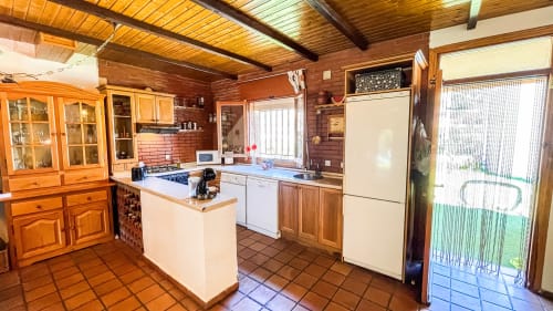 Cocina rústica de madera con isla, electrodomésticos blancos y baldosas de terracota en Casa Rural Villa del Jerte, El Torno Cáceres