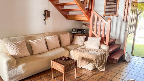Sofá seccional beige con cojines en la sala de estar de Casa Rural Villa del Jerte, escalera de madera visible, El Torno