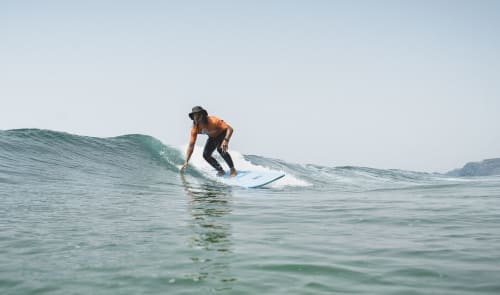 Surfer riding a wave in Bordeira, Portugal at Star Host with ocean and coastal cliffs visible