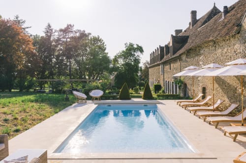 Piscine du Prieuré Du Preux avec chaises longues, parasols et bâtiment en pierre à Sépeaux Saint Romain
