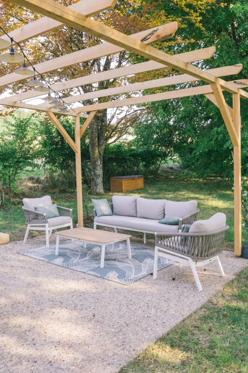 Espace de détente en plein air sous une pergola en bois à Le Prieuré Du Preux avec mobilier et vue sur le jardin