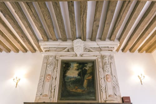 Plafond classique aux poutres apparentes et élégante cheminée en pierre au Prieuré Du Preux, un gîte français