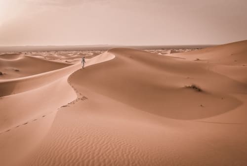 Eenzame reiziger die door gouden Saharazandduinen loopt in de buurt van Marrakesh, Marokko