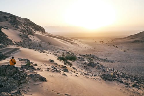 Woestijnreiziger in geel jack genietend van gouden duinen bij Marrakesh, Marokko