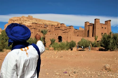 Persoon in blauwe tulband kijkend naar Kasbah Ait Benhaddou, een traditioneel leemfort in Marrakesh, Marokko