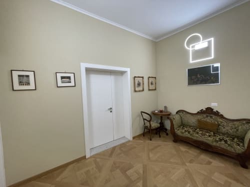 Appartamento Saint Michel a Gorizia con elegante soggiorno, pavimento in legno, divano antico, opere d'arte incorniciate e porta bianca