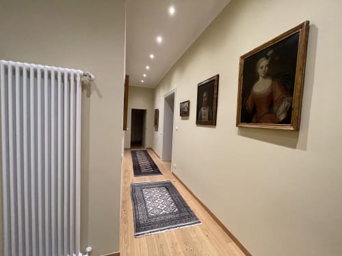 Elegante corridoio dell'hotel apartamento Saint Michel a Gorizia con ritratti incorniciati, pavimenti in legno e illuminazione moderna