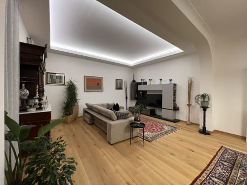 Moderno appartamento a Saint Michel Gorizia con divano beige, pavimenti in legno, illuminazione contemporanea e vista sulla città