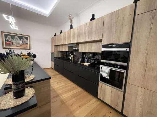 Cucina moderna nell'appartamento di Saint Michel a Gorizia con mobili in legno, isola nera e elettrodomestici in acciaio inox