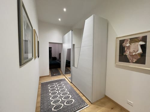 Elegante corridoio dell'appartamento Saint Michel a Gorizia, con guardaroba bianco, quadri incorniciati e tappeto geometrico