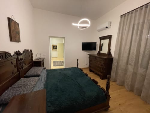Camera da letto Saint Michel a Gorizia con mobili in legno scuro, letto verde, TV a schermo piatto, lampada neon a forma di pianeta, e