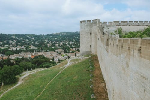 Medieval stone fortress wall overlooks green hillside and village of Morières-lès-Avignon, France