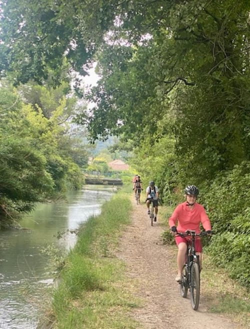 Cyclists riding on scenic towpath along canal near Domaine des Lavarines, Morières-lès-Avignon