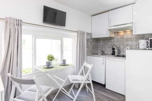 Modern studio kitchenette with white dining table, chairs, and equipped kitchen at Azur Studios Cannes