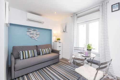 Superior Studio at Azur Studios Cannes with gray sofa, blue accent wall, striped rug, and dining area by windows
