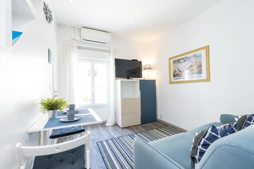 Modern studio apartment at Azur Studios Cannes with sofa, dining table, kitchenette, TV, and city view from private entrance