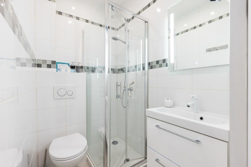 Modern bathroom in Superior Studio at Azur Studios Cannes featuring glass shower enclosure, white vanity, and gray tile