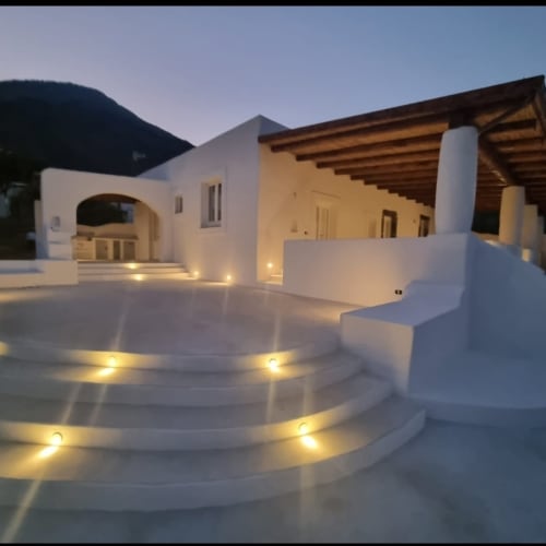 Miravilla Salina terrace at dusk with illuminated circular platform, white walls, wooden pergola, and mountain backdrop in