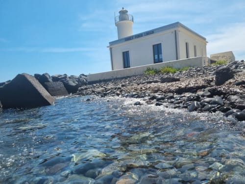 Lighthouse at Miravilla Salina B&B overlooking rocky coastline in Santa Marina Salina, Sicily
