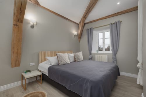 Lichte slaapkamer in Moulin Renaudiots in Autun met blootliggende houten balken, tweepersoonsbed, tuinzicht en moderne voorzieningen