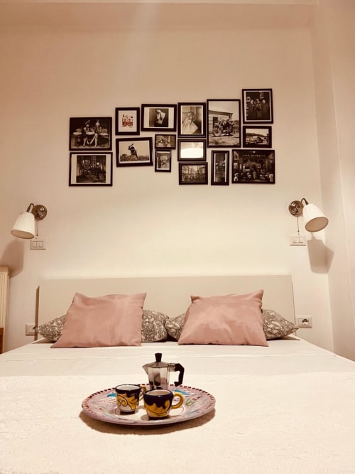 Camera elegante di Casa Castagna B&B a Salerno con cuscini rosa, parete galleria foto vintage e servizio caffè sul letto
