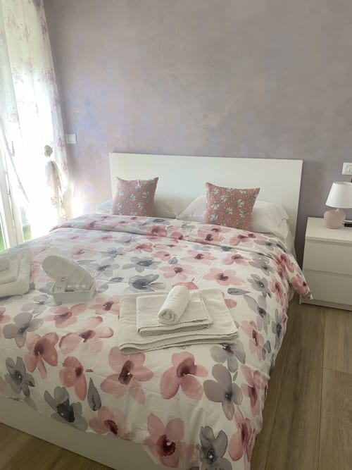 Bedroom at Maryam 23 B&B in Siracusa with floral bedding, white headboard, and city view