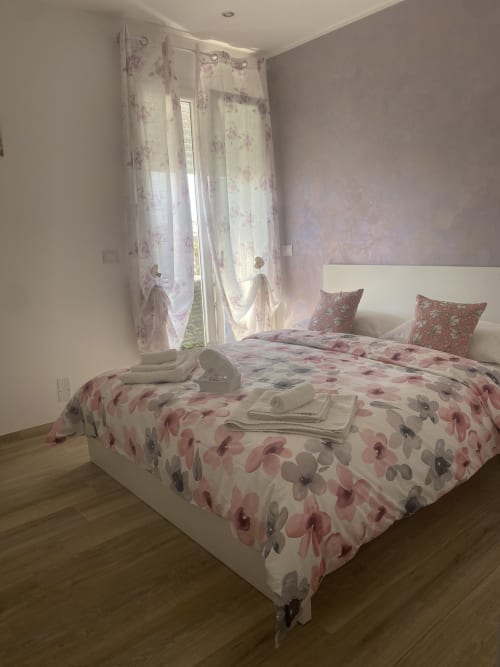 Pink floral bedroom with balcony at Maryam 23 B&B in Siracusa, featuring double bed and city views