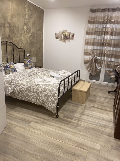 Double bed room at Maryam 23 B&B in Siracusa with balcony, striped curtains, and wooden floors