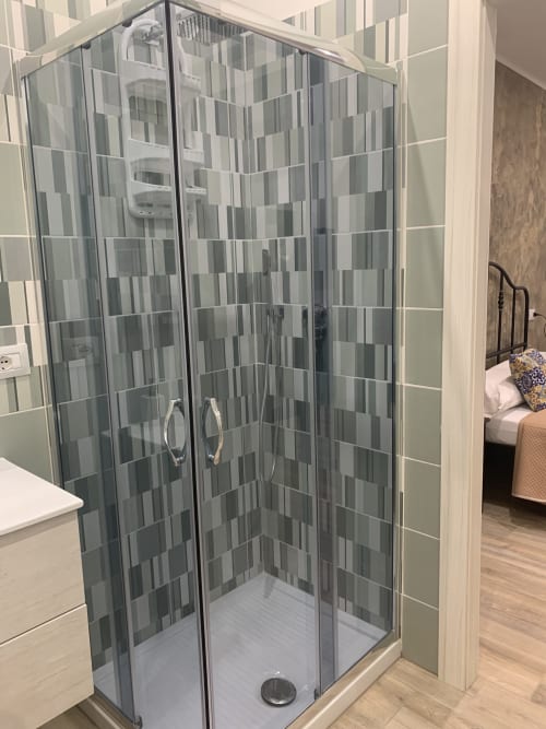 Modern glass shower enclosure with grey tile pattern in Maryam 23 Siracusa hotel room