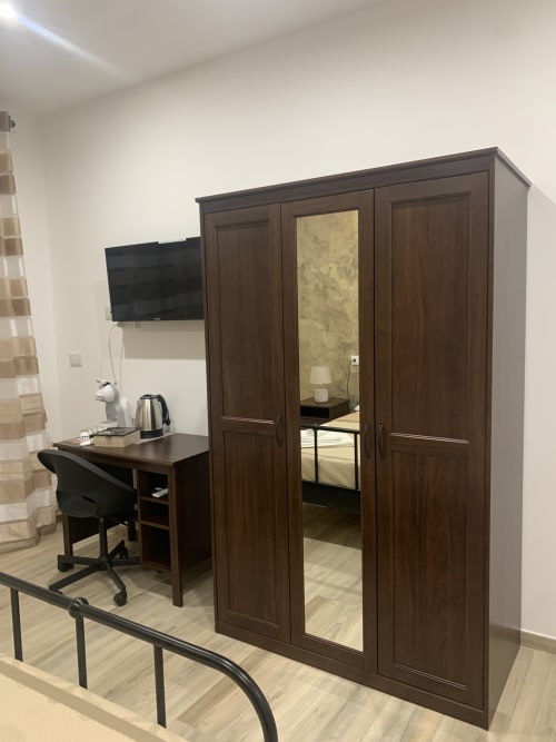Dark wooden wardrobe with mirror doors in Maryam 23 Siracusa double deluxe room, desk with TV and chair
