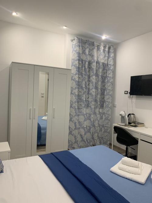 Modern double bedroom at Maryam 23 B&B in Siracusa with blue bedding, wardrobe, work desk, and blue floral curtains