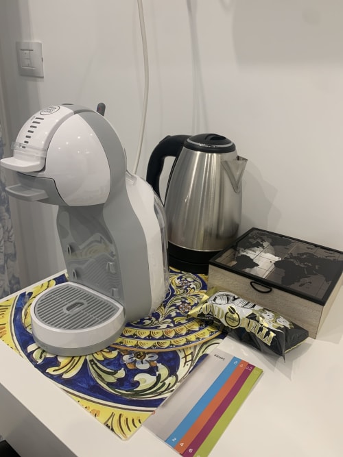 Coffee station in Blue Room at Maryam 23 B&B, Syracuse, with white machine, kettle, and decorative mat