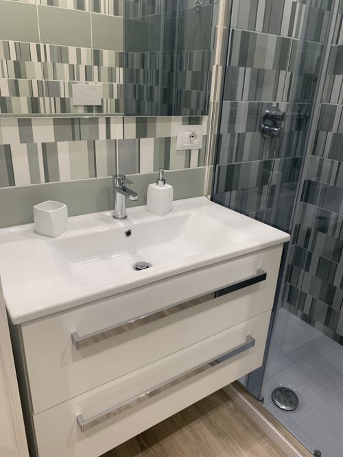 Modern bathroom at Maryam 23 BnB in Siracusa with white vanity, striped tile walls, and shower enclosure