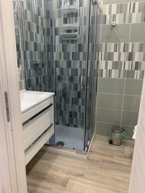 Modern bathroom at Maryam 23 B&B Siracusa with glass shower, geometric tile design, and white vanity
