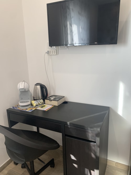 Maryam 23 hotel room in Siracusa with wall-mounted TV, desk with kettle and amenities, black chair