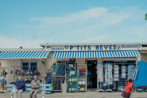 Charmante boutique côtière aux auvents bleu et blanc à Trouville-sur-Mer, vendant jouets et souvenirs