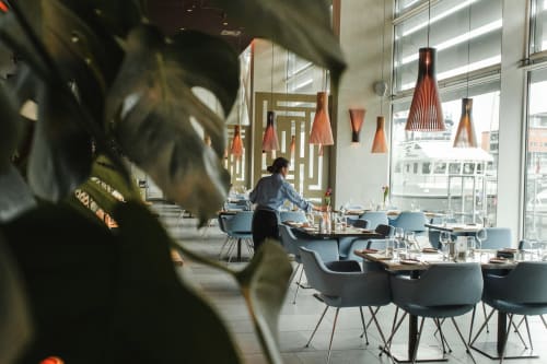 Salle à manger contemporaine de l'Hôtel Le Trouville avec chaises bleues, luminaires suspendus en bois et vue côtière