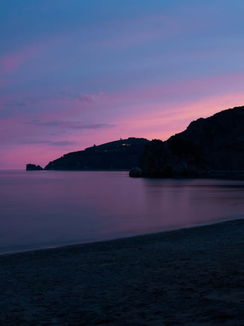 Twilight coastal view of Casa Castagna's beach in Salerno, Italy with silhouetted cliffs and calm waters