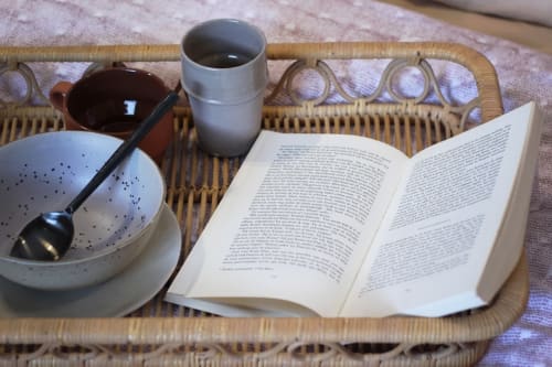 Petit-déjeuner cosy au Prieuré Du Preux avec livre ouvert, tasse de café et bol en céramique sur table en rotin