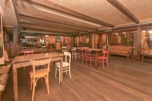 Sala da pranzo dell'Hotel Le Clou ad Arvier con tavoli in legno, sedie e soffitto con travi a vista