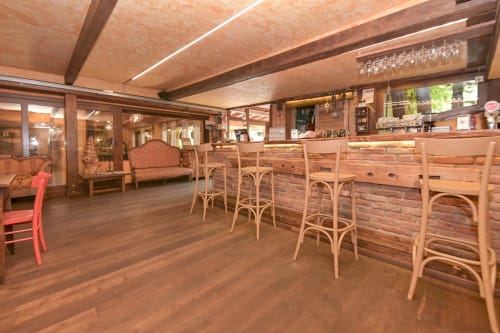 Interno caldo in legno del bar Hotel Le Clou con sedie in legno curvato, parete in mattoni e illuminazione moderna ad Arvier